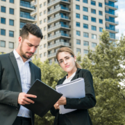 close-up-businessman-businesswoman-holding-documents-standing-front-building
